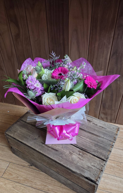 Pretty in Pink - A beautifully hand-tied bouquet featuring soft ivory and vibrant pink tones, delicately arranged with textured accents and lush greenery. Wrapped in striking pink presentation and finished with a coordinating bow, this elegant design is perfect for celebrating special moments, sending love, or brightening someone’s day.