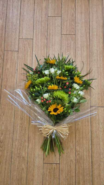 Tied Sheaf - A graceful hand-tied sympathy bouquet designed to offer warmth, comfort, and remembrance. Featuring a harmonious blend of soft textures, fresh greenery, and radiant seasonal tones, this arrangement brings a gentle sense of peace and natural beauty to memorial services, celebrations of life, or thoughtful condolence gestures. Wrapped in clear presentation film with rustic detailing, it creates an elegant and heartfelt tribute.